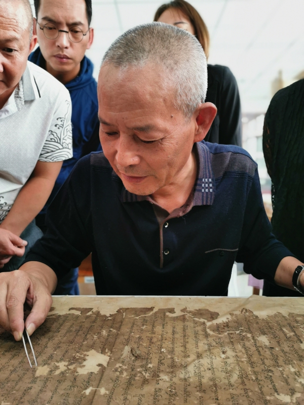یانگ لیکون (جلو) یک نسخه خطی باستانی را همانطور که شاگردانش مشاهده می کنند بازیابی می کند. 